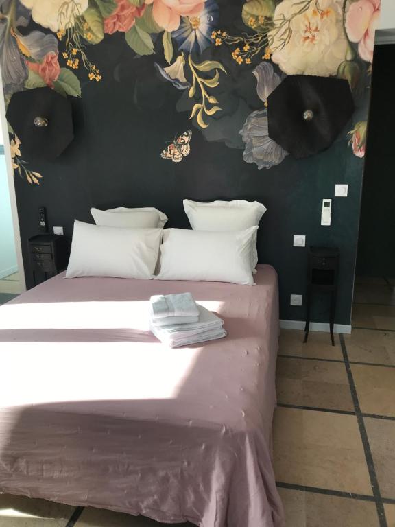 1 dormitorio con 1 cama con flores en la pared en LA CASA SANILLS, en Saint-Hippolyte