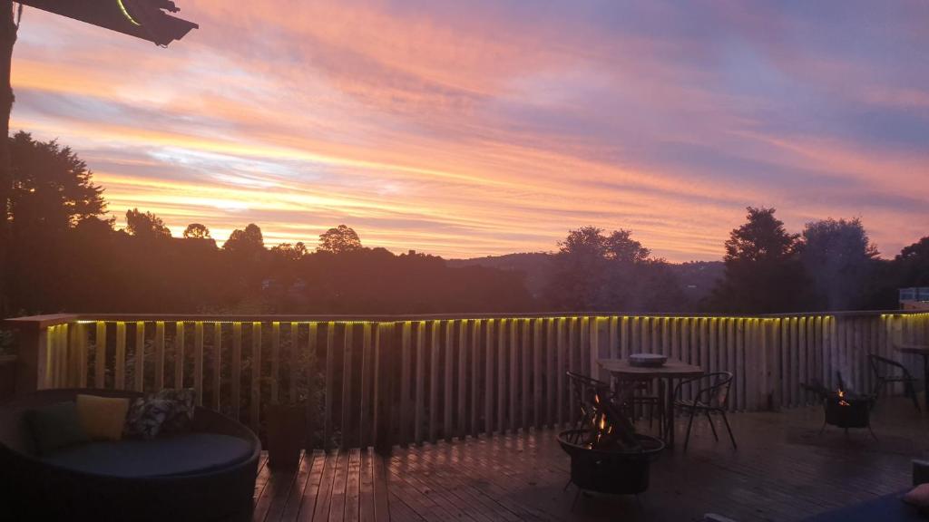 a sunset over a deck with a table and a fence at Recanto dos Moinhos - Boutique Hotel in Campos do Jordão