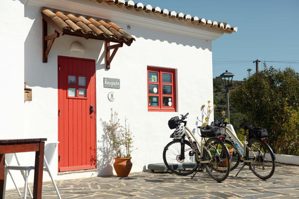 two bikes parked outside of a building with a red door at Aldeia da Pedralva - Slow Village in Vila do Bispo
