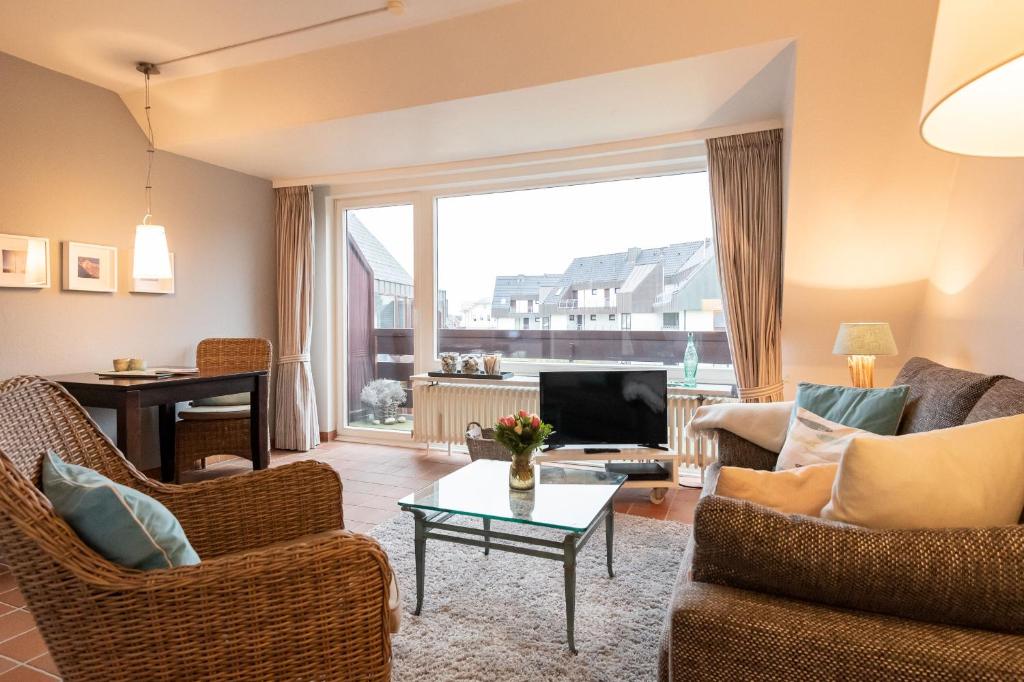 a living room with a couch and a tv and a table at Syltdomizil Tade, App 1 in Wenningstedt