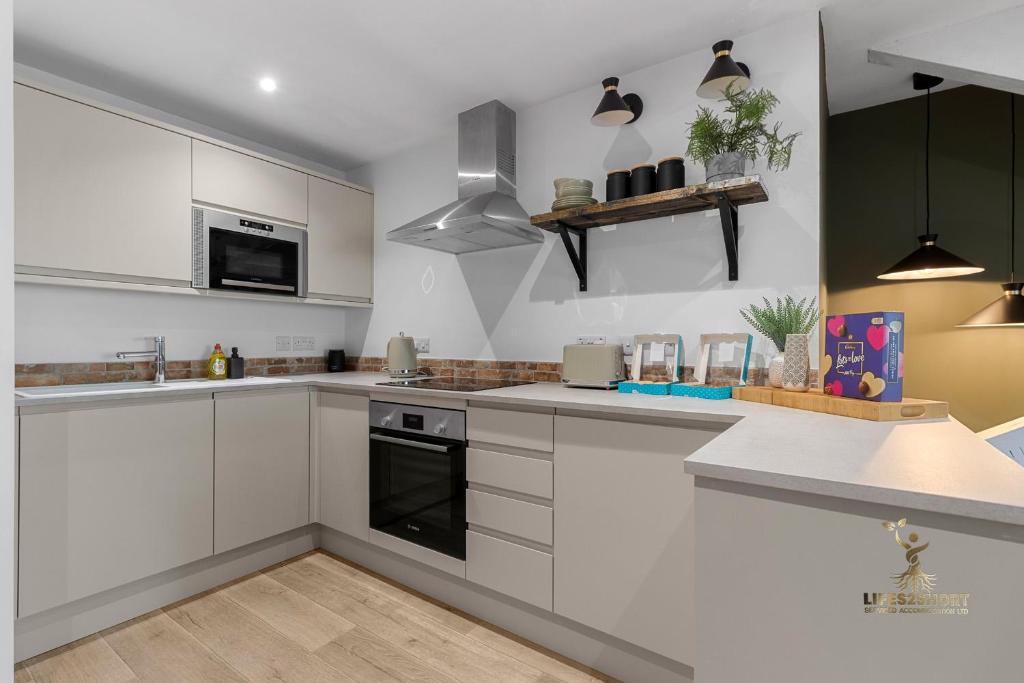 a kitchen with white cabinets and stainless steel appliances at Luxe Courtyard Apartment for 4 Near Exeter City Centre in Exeter