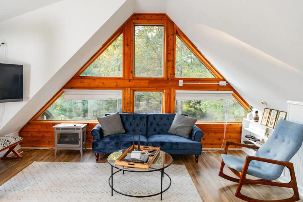 a living room with a blue couch and some windows at HOT TUB Charming & Chic Mountain Gem On Sleepy Creek in Berkeley Springs