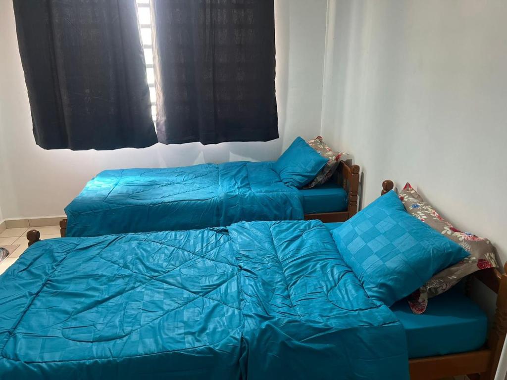 2 bedden met blauwe lakens in een slaapkamer bij Sobey Laris Homestay RP in Pasir Mas