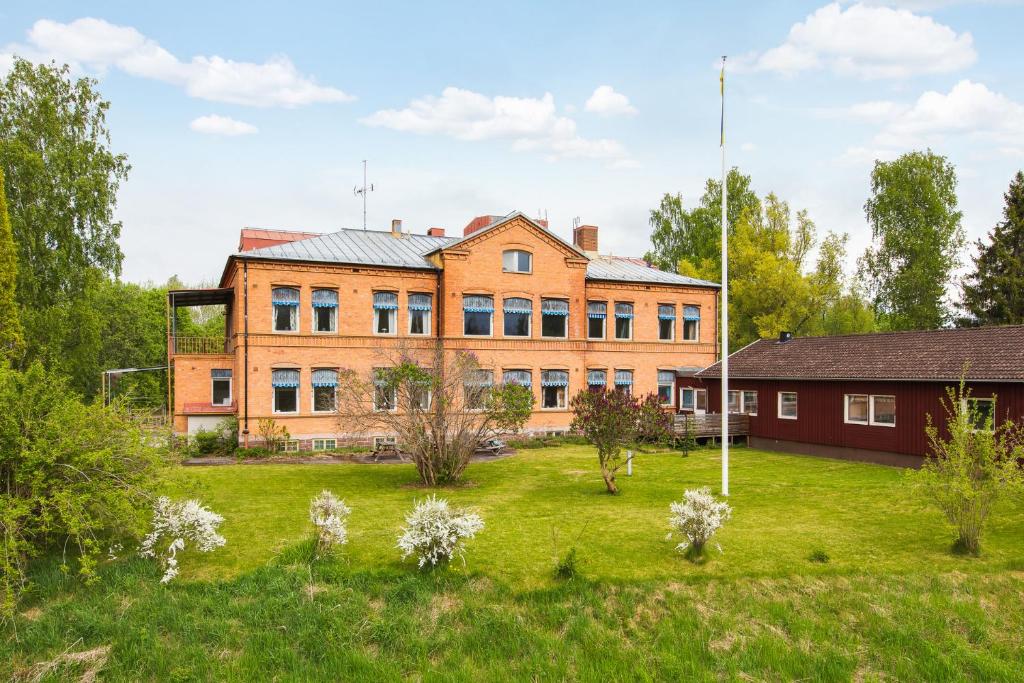 ein altes Backsteingebäude mit einem Grasfeld davor in der Unterkunft Näsbygården in Storvik