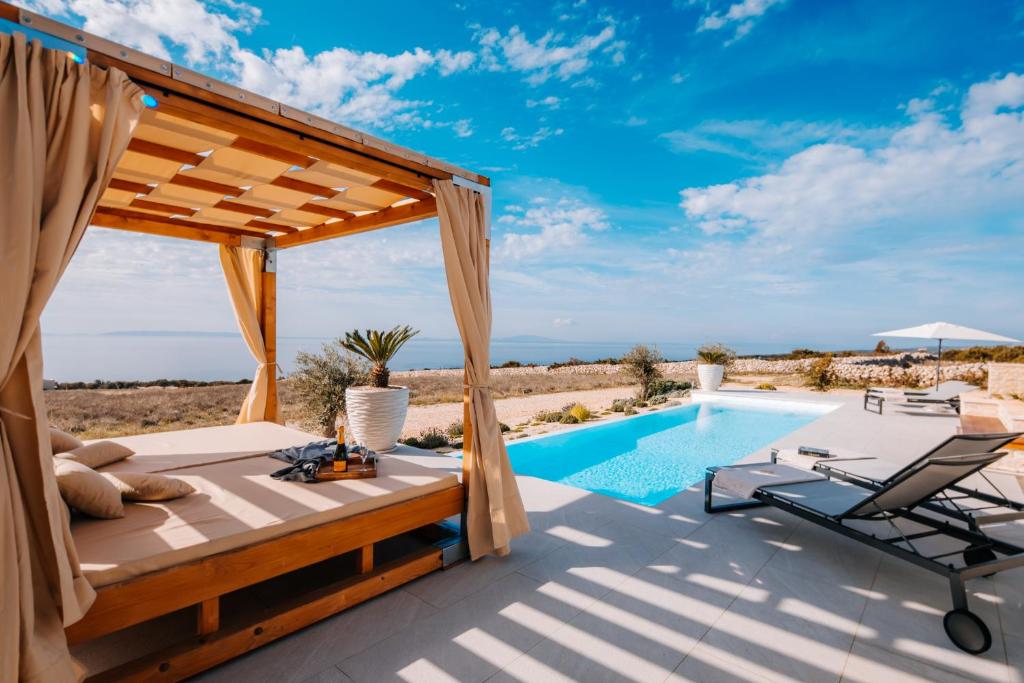 a patio with a bed and a swimming pool at Luxury villas on Island Pag - Plant Villas Novalja in Novalja