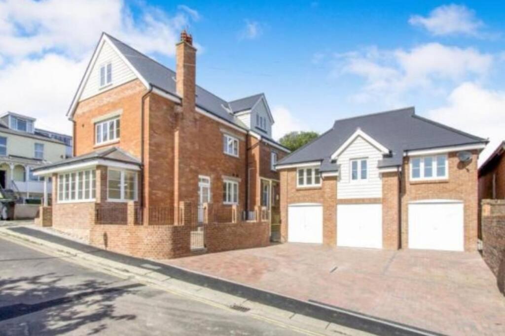 a large brick house with white garage doors at Stones Throw-near harbour & beach Pet Friendly in Weymouth