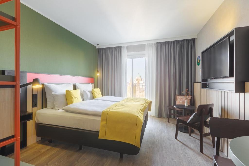 ein Hotelzimmer mit einem Bett und einem Flachbild-TV in der Unterkunft acora Potsdam Living the City in Potsdam
