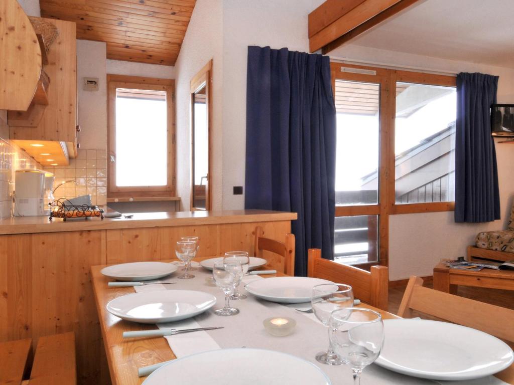 une salle à manger avec une table, des assiettes et des verres dans l'établissement Appartement chaleureux au pied des pistes avec balcon, 3 pièces, 7 pers., animaux admis - FR-1-181-2200, à La Plagne Tarentaise
