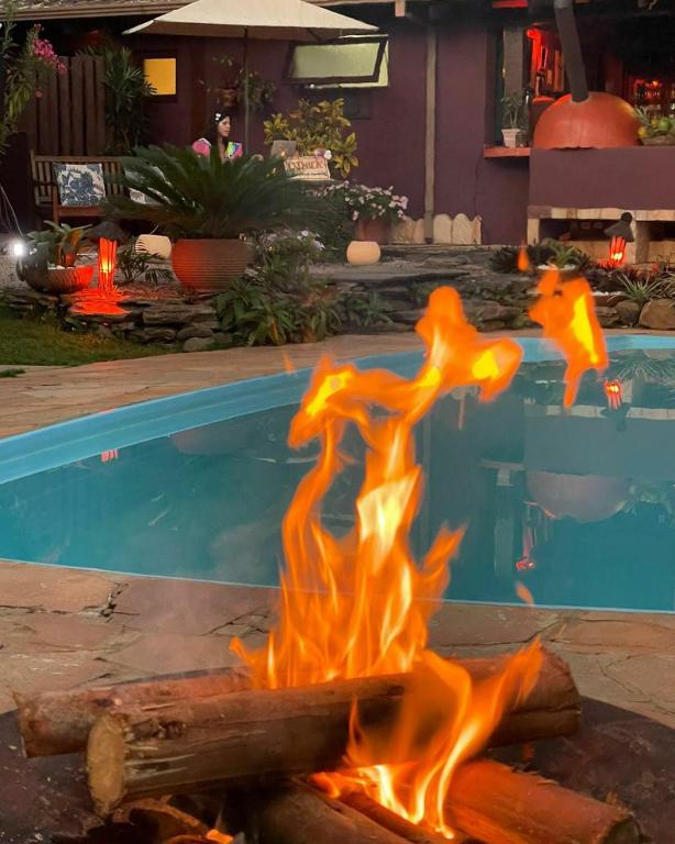 a fire pit in front of a swimming pool at Pousada Maya in Alto Paraíso de Goiás