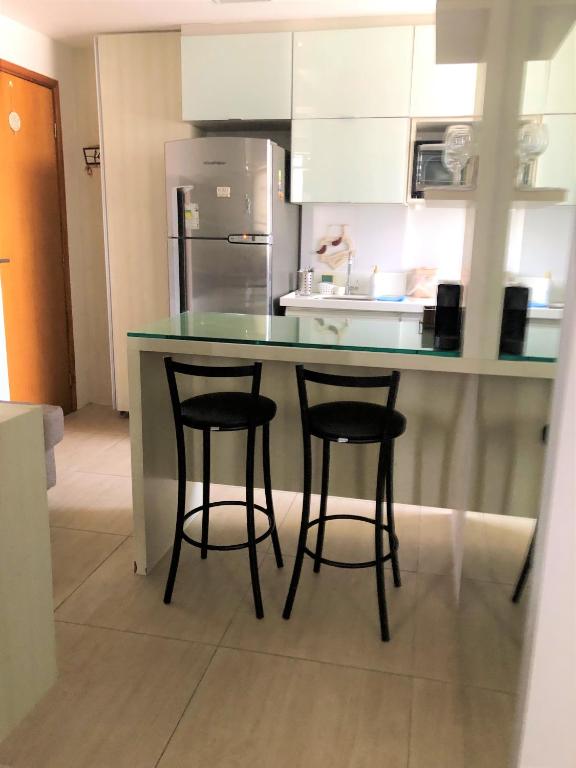 a kitchen with two bar stools and a counter top at Boa Viagem - Charmoso apartamento para casais in Recife