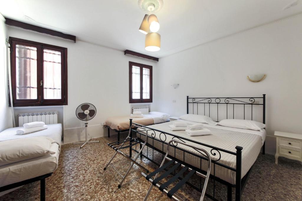um quarto com 3 camas, uma mesa e uma ventoinha em San Stae Apartment WIFI AC em Veneza
