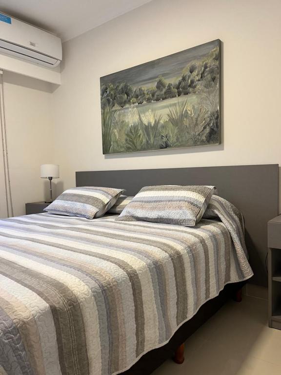 2 camas en un dormitorio con una pintura en la pared en Apart France - Un dormitorio con gim, piscina y estacionamiento en Río Cuarto