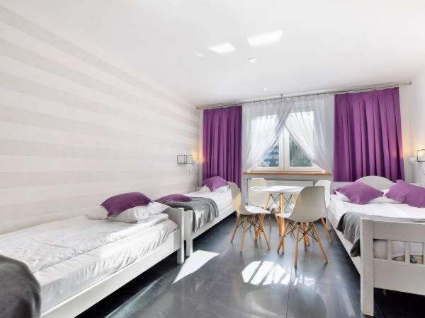 a bedroom with three beds and a table and chairs at Willa Marion in Karpacz