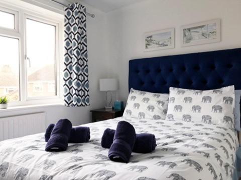 1 cama con cabecero azul y almohadas en KB99 Comfy 2 Bedroom House in Horsham, pets very welcome with easy links to London and Gatwick, en Roffey