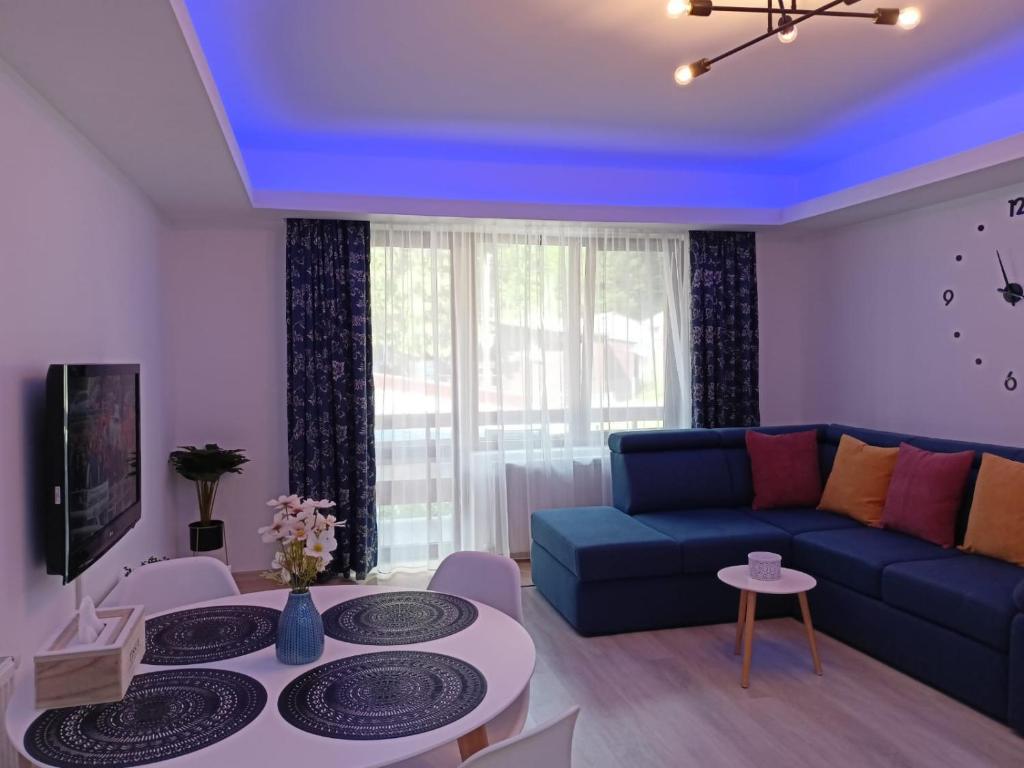a living room with a blue couch and a table at Apartament Eric, Busteni in Buşteni