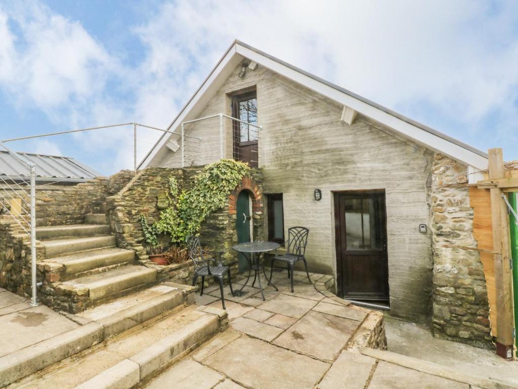 a stone house with a table and chairs on a patio at Green Grove Barn in Carmarthen