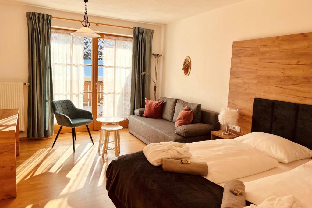 1 dormitorio con 1 cama y sala de estar con sofá en Wellnesshotel Waldruh, en Bad Kohlgrub