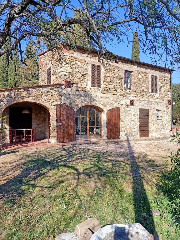 une ancienne maison en pierre avec une grande cour dans l'établissement Il Casolare del Pastore, à Suvereto