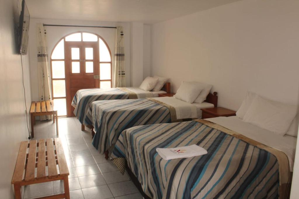 a hotel room with three beds and a window at MESONERO in Ayacucho