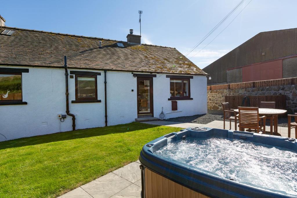 a hot tub in a yard next to a house at Cannich Cottage at Parbroath Farm in Cupar
