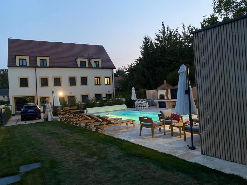 a backyard with a pool and chairs and a house at VILLA MAGNYSOLAR Proche Disneyland Paris in Magny-le-Hongre