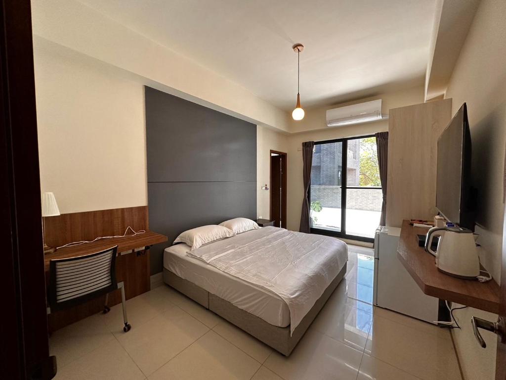 內埔鄉的住宿－愛瑪仕民宿，一间卧室配有一张床、一张书桌和一台电视