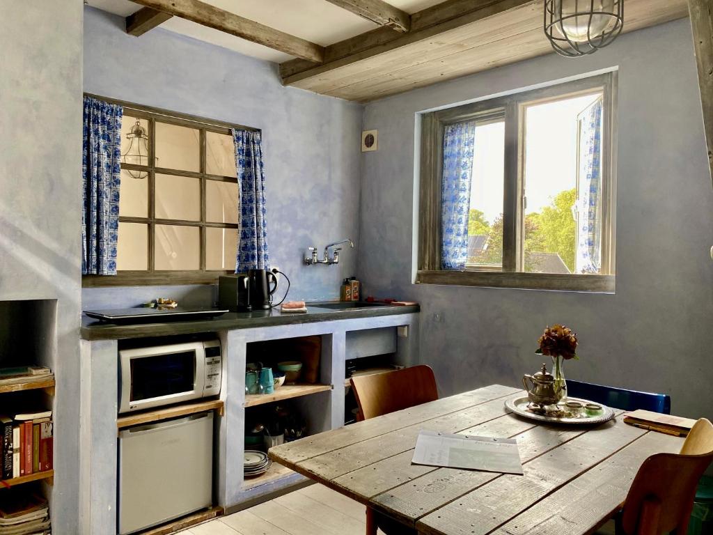 a dining room with a table and a kitchen with a window at In de Aap - Appartementen & Guesthouse in Bergen
