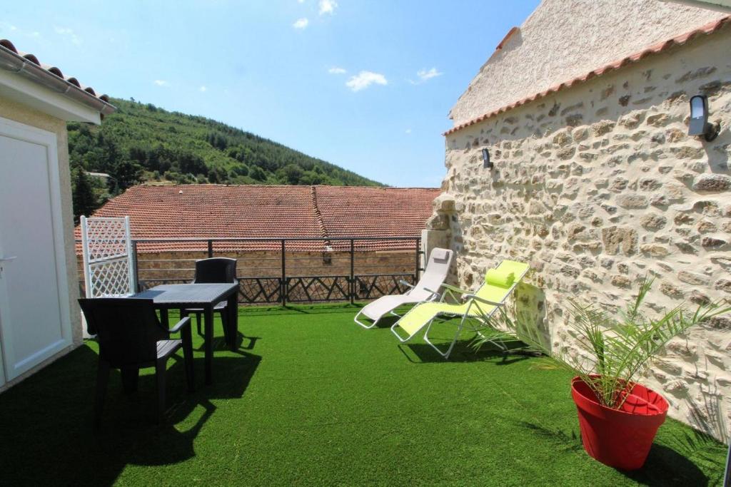 un patio con césped verde, mesa y sillas en Gîte L'armu avec Spa Privé en Savas