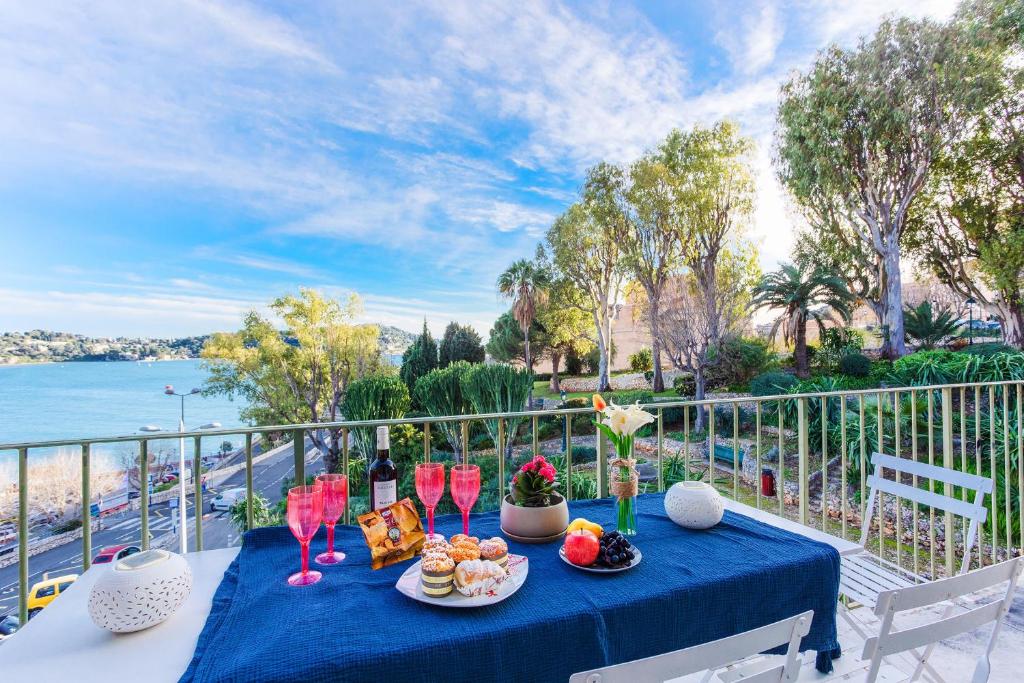 une table bleue avec de la nourriture et des boissons sur un balcon dans l'établissement Le Mary Jane AP4335, à Villefranche-sur-Mer