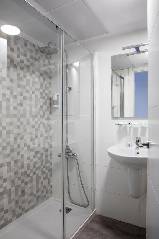 a bathroom with a glass shower and a sink at Hotel Tugasa Arco de la Villa in Zahara de la Sierra