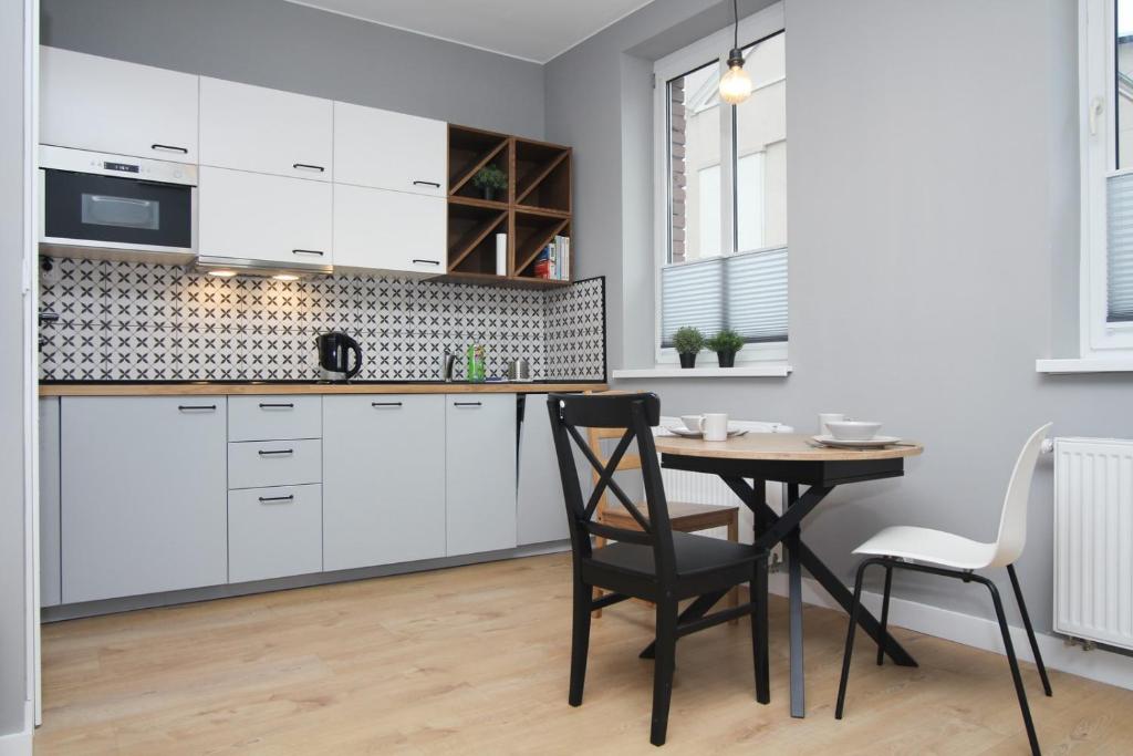 uma cozinha com armários brancos e uma mesa e cadeiras em Stara Drukarnia - Apartamenty typu Studio em Bydgoszcz