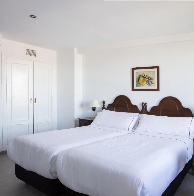 a bedroom with a large white bed with white sheets at Hotel Tugasa Arco de la Villa in Zahara de la Sierra