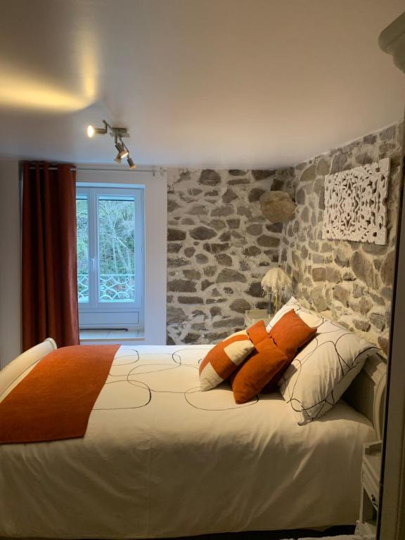 1 dormitorio con cama con almohadas y pared de piedra en Petit coin de paradis, en Vals-les-Bains