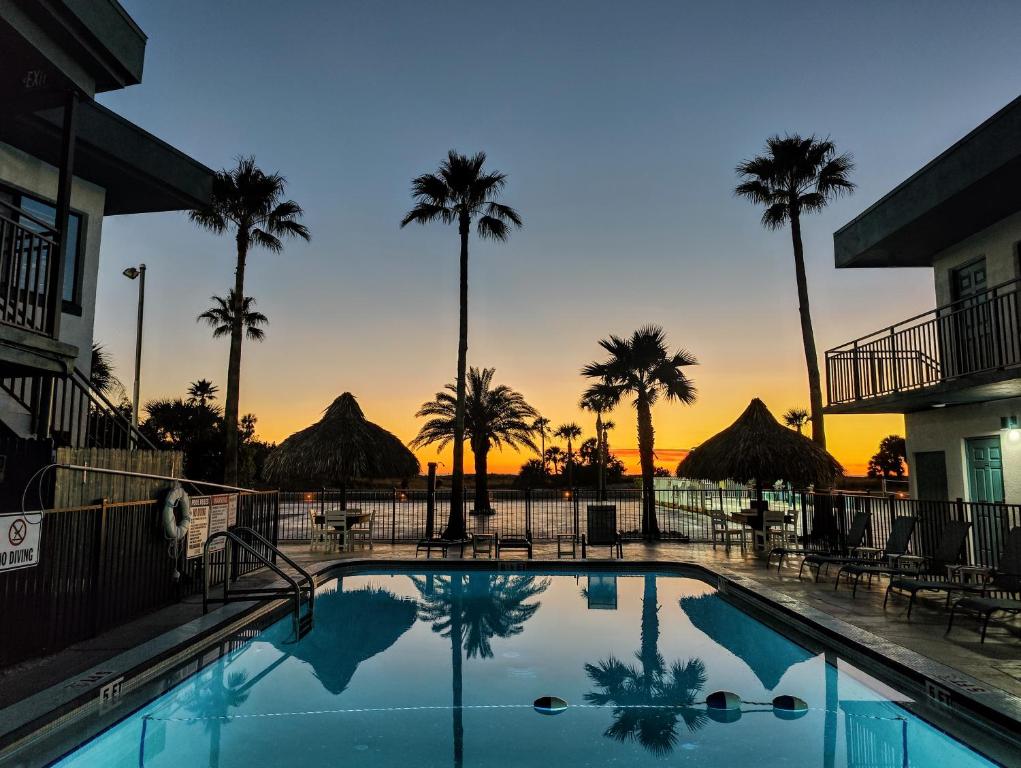 uma piscina com palmeiras e um pôr-do-sol ao fundo em Tahitian Beach Resort em St. Pete Beach