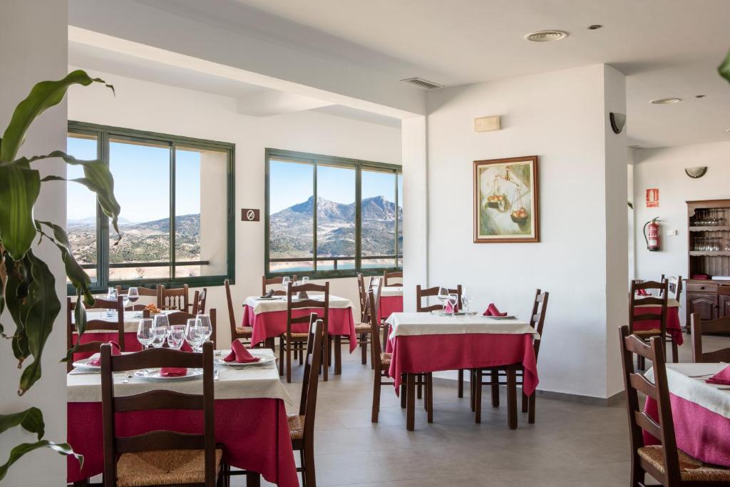 a restaurant with tables and chairs with mountains in the background at Hotel Tugasa Arco de la Villa in Zahara de la Sierra