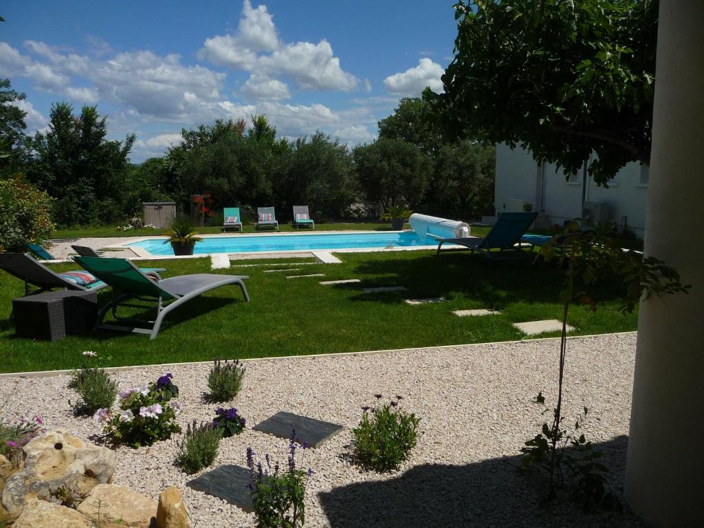 a backyard with a swimming pool with chairs and plants at L'Ostal Randoleta in Abeilhan