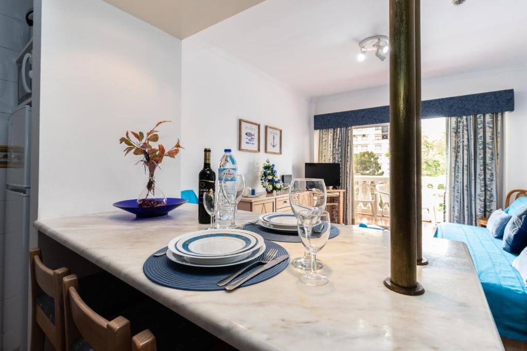 una mesa de comedor con platos y vasos. en Parque dos Reis Apartment, en Monte Gordo