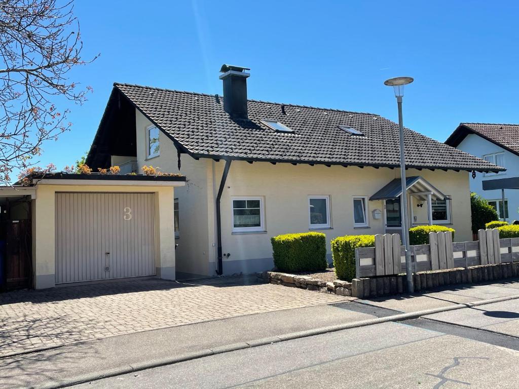 a white house with a garage and a fence at Ferienwohnung Lang - schöne 3-Zimmer-Wohnung in Bonndorf im Schwarzwald