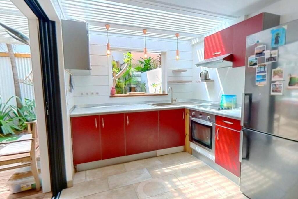 a kitchen with red cabinets and a red refrigerator at Calme et apaisant in La Saline les Bains