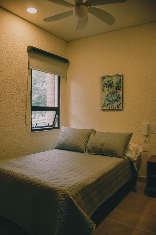 a bedroom with a bed with a fan and a window at Bunde Haus Hotel EXPRESS BOUTIQUE in Ibagué