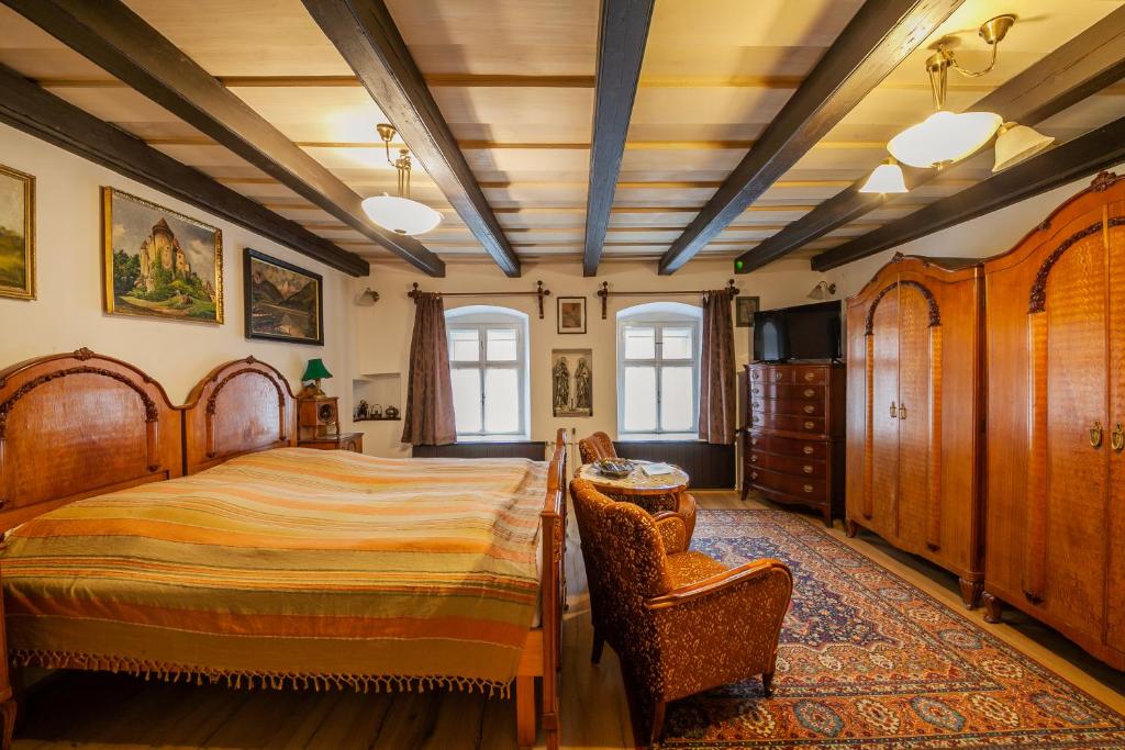 a bedroom with a bed and a chair and windows at Sziget Vendégház in Kőszeg