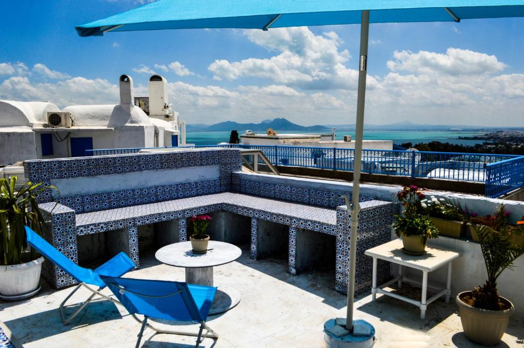 um pátio com uma mesa, cadeiras e um guarda-sol em Cosy S3 Apartment in Sidi Bou Said Village em Sidi Bou Saïd