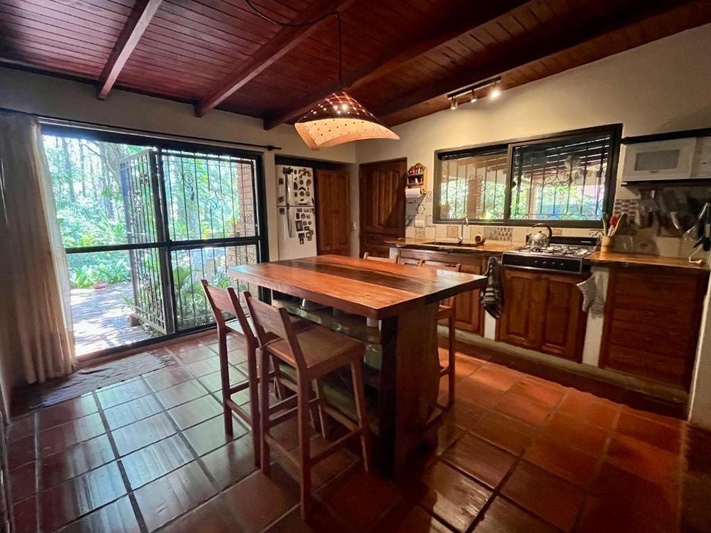 cocina con mesa de madera y algunas ventanas en Casa Jaguar en Puerto Iguazú