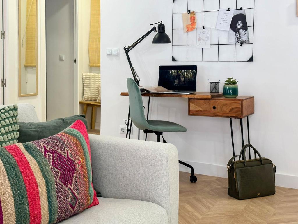 a living room with a chair and a desk with a laptop at Elegante apartamento a unos pasos de la Rambla. in Alicante