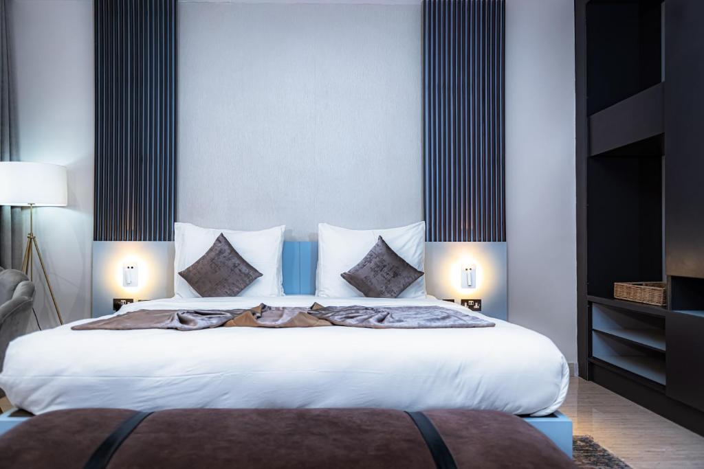 Wali's Suites في أبوجا: غرفة نوم بسرير كبير عليها شراشف ووسائد بيضاء