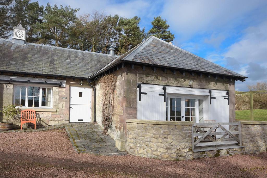 a stone building with a white door and a gate at Harness Lodge in Seahouses