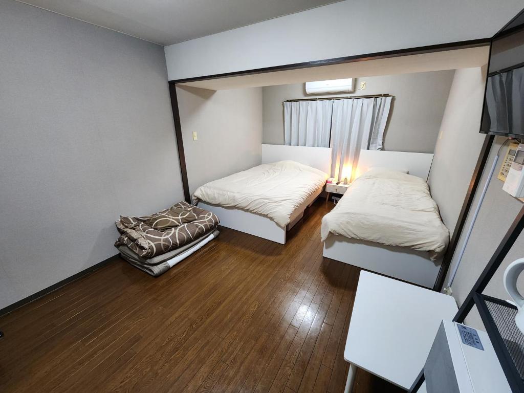 Habitación pequeña con 2 camas y mesa. en MORI Apartment2 道頓堀(Dotonbori) 1K, en Osaka