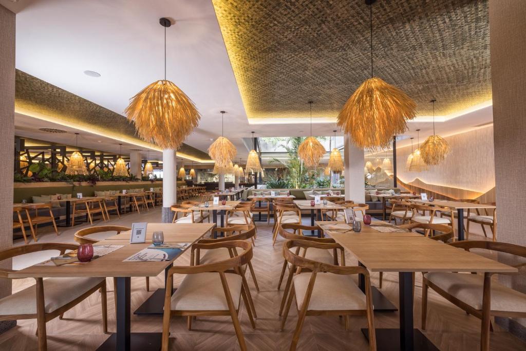 a restaurant with tables and chairs and chandeliers at MYND Yaiza in Playa Blanca