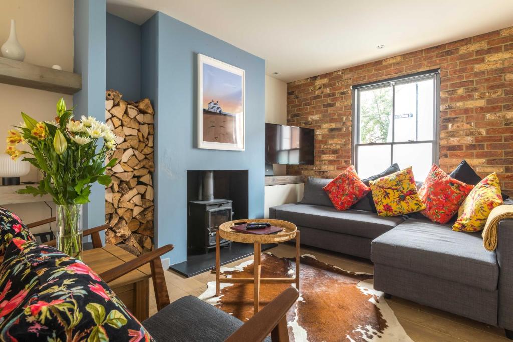 a living room with a couch and a brick wall at White Cottage in Whitstable