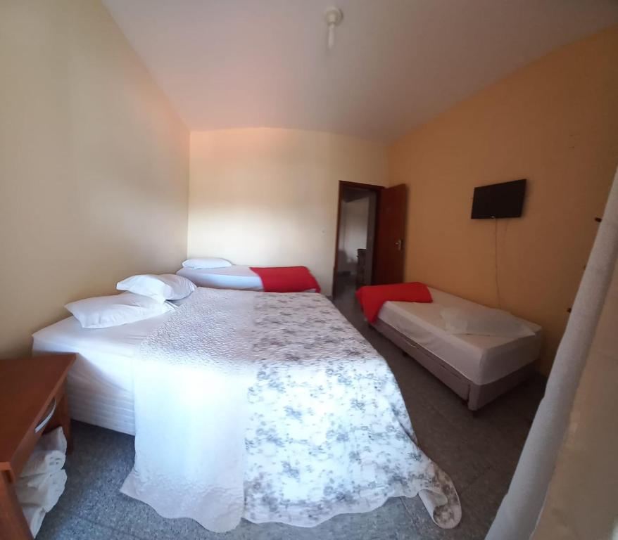 a bedroom with two beds and a tv in it at Santa Helena Pousada in Cachoeira Paulista